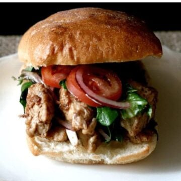 Close up of a balsamic chicken ciabatta sandwich with tomato and red onion