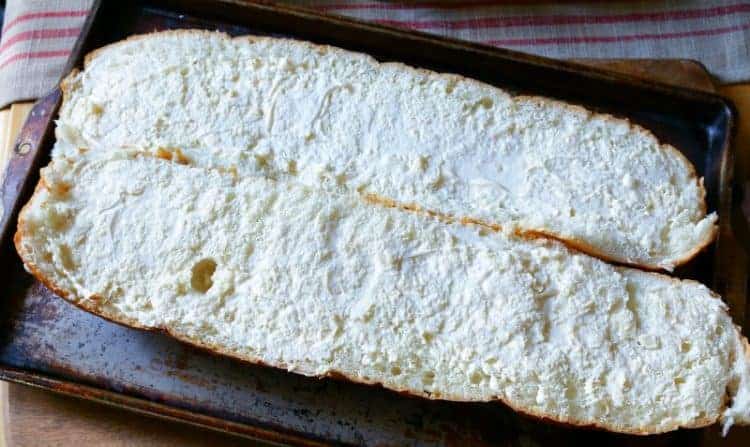 Mayonnaise spread over French bread on cookie sheet