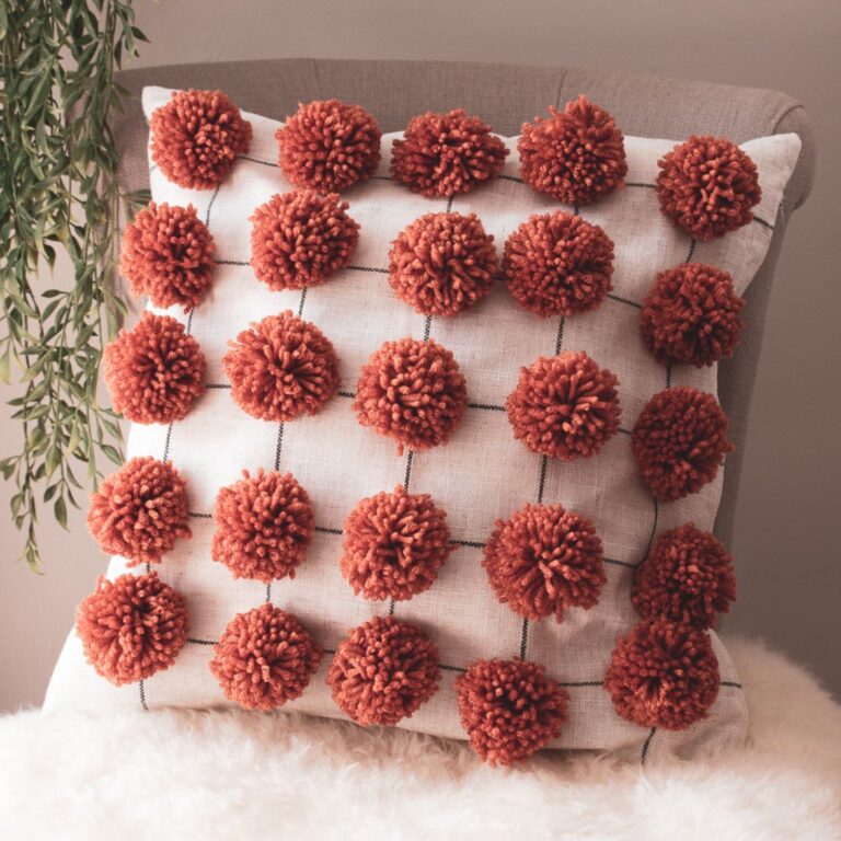 Close up of a homemade pom pom pillow with pom poms on an 18 x 18 linen pillow cover