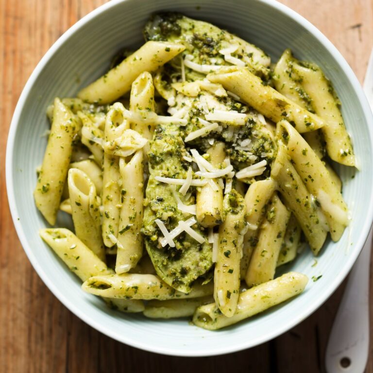 overhead view of pasta topped with pesto and parmesan cheese