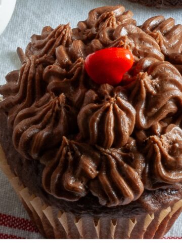 Close up view of a homemade chocolate covered strawberry cupcake with a homemade chocolate buttercream frosting