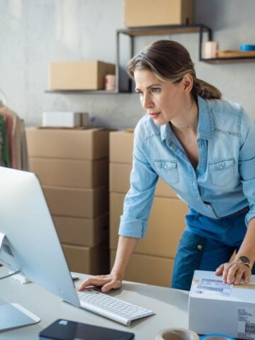 beautiful middle aged woman business owner adding shipping labels to orders for her business