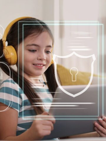 A young girl with pigtails and yellow headphones sits on a couch, smiling as she looks at a tablet. The image includes digital graphics overlaying the scene, featuring a shield with a keyhole symbol, indicating security, and various data charts and graphs, representing technology and information security. The background shows a cozy, well-lit living room, adding to the comfortable and modern ambiance.