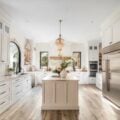 Bright white kitchen with marble countertops, black hardware, warm wood floors and gold pendant lights created with Midjourney AI