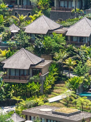 A collection of luxury villas nestled in lush tropical greenery in Bali, featuring private pools and traditional Balinese architectural elements. This image highlights Bali’s upscale real estate opportunities, catering to high-end investors and vacation home buyers.