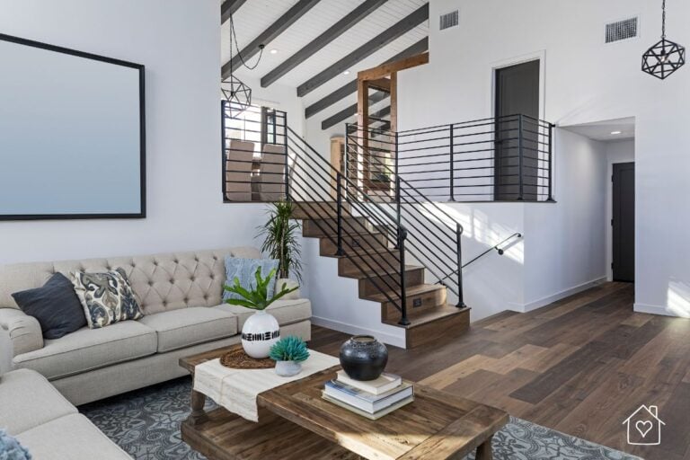 A chic yet budget-friendly living area with a tufted beige sofa, a wooden coffee table, and modern metal railings, blending rustic charm with contemporary style.