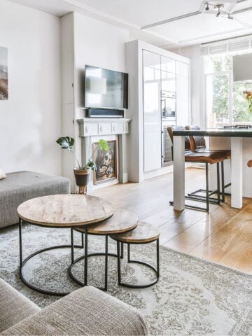 A stylish small home living room connected to a modern kitchen with a central island, bar stools, and space-saving furniture to enhance flow and functionality.