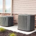 Two central air conditioning units outside a home, showcasing a well-maintained cooling system.