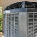 Close-up of a residential central air conditioning condenser unit with protective grill and side vents.