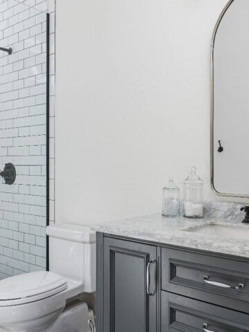 Modern black and white bathroom with subway tile shower and marble vanity, highlighting efficient and stylish plumbing fixtures.