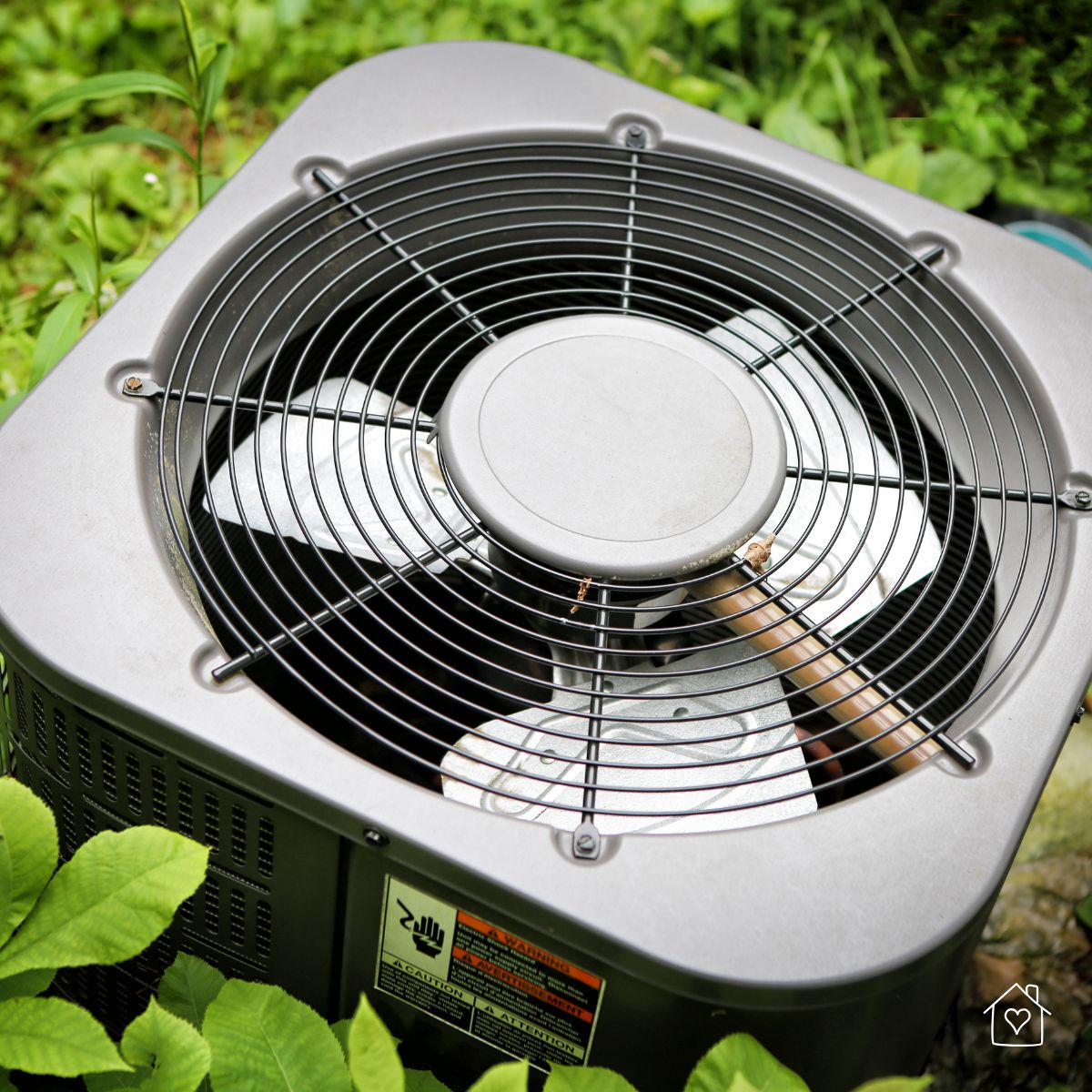 Close-up of a central air conditioning unit surrounded by greenery, potentially indicating a system in need of maintenance or repair.