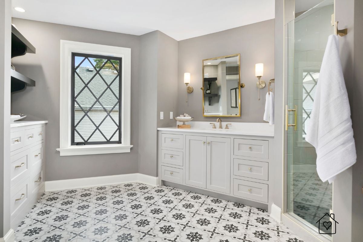 Bright bathroom showcasing decorative black and white patterned tile flooring, gray walls, and gold accents for a modern vintage feel.