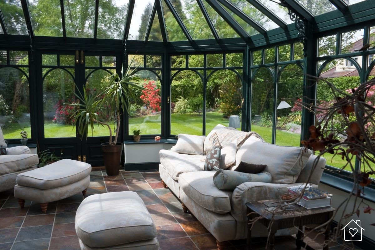 A classic conservatory with plush seating and slate tile flooring, offering a serene flexible living area surrounded by garden views.