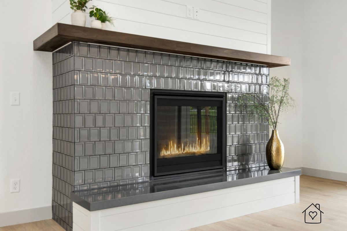 Living room fireplace clad in glossy gray square subway tiles with a dark wood mantel and sleek built-in bench for a cozy modern look.