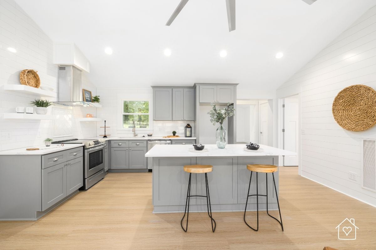 Freshly renovated kitchen with gray cabinets, light wood flooring, and bright white walls, showcasing modern home improvement.