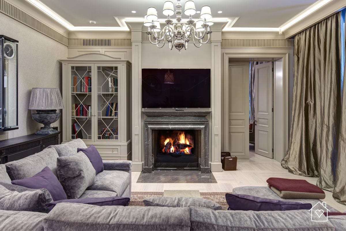 Traditional living room with fireplace, chandelier, and heavy drapes, representing a space that may need modern updating.