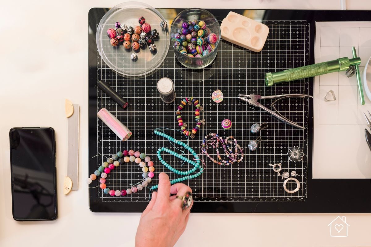 A workspace with handmade polymer clay beads, bracelets, and tools on a cutting mat, highlighting accessories that beginners can create.