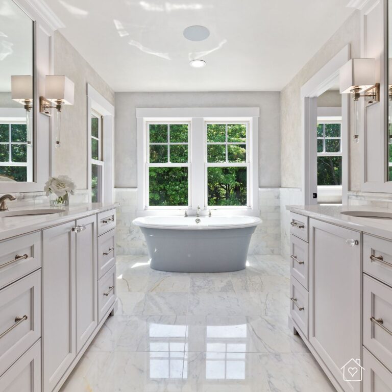 Updated bathroom with marble floors, freestanding tub, and natural light, showing how a renovation enhances everyday living.