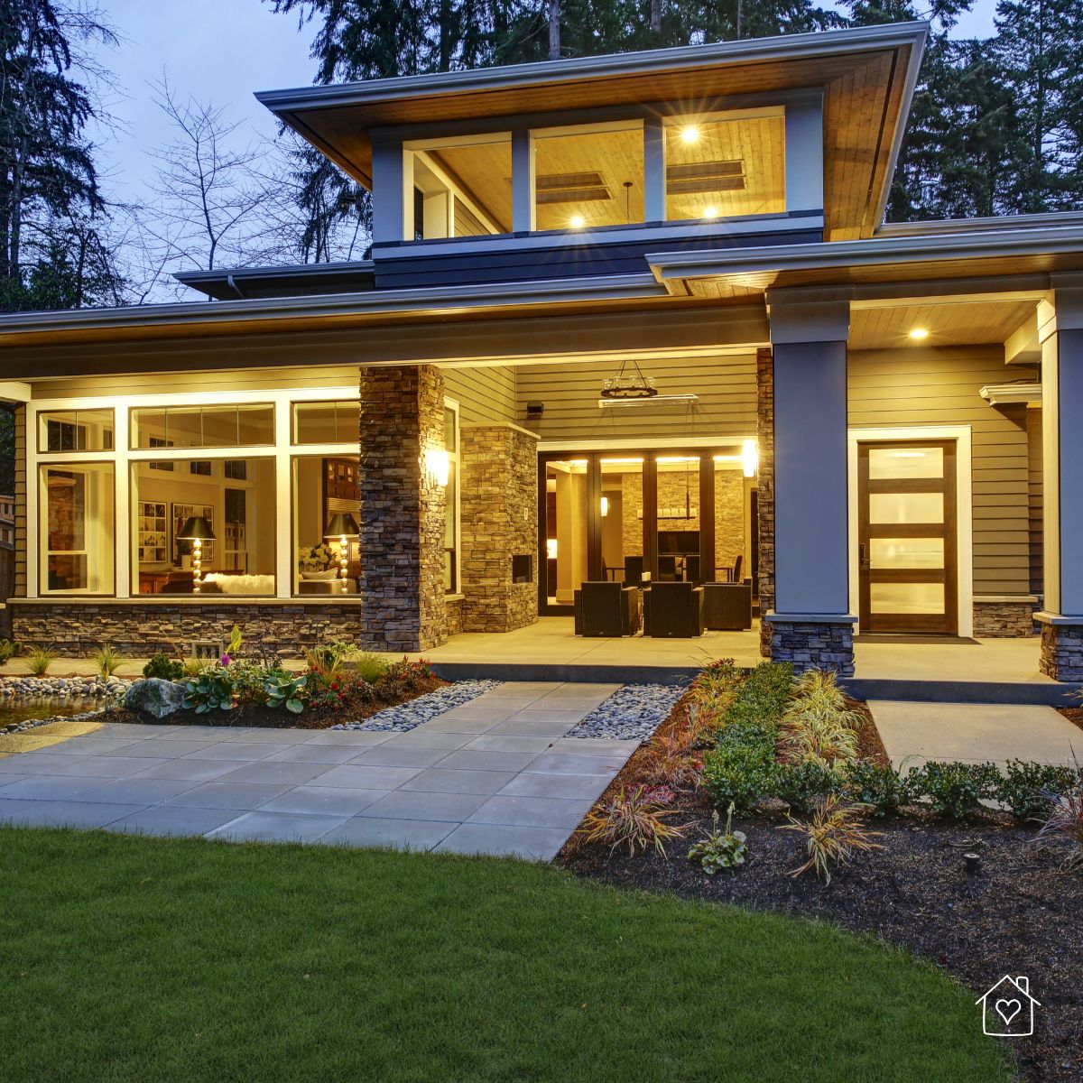 Well-lit modern home exterior with stone pillars and large windows, showcasing weather protection features.