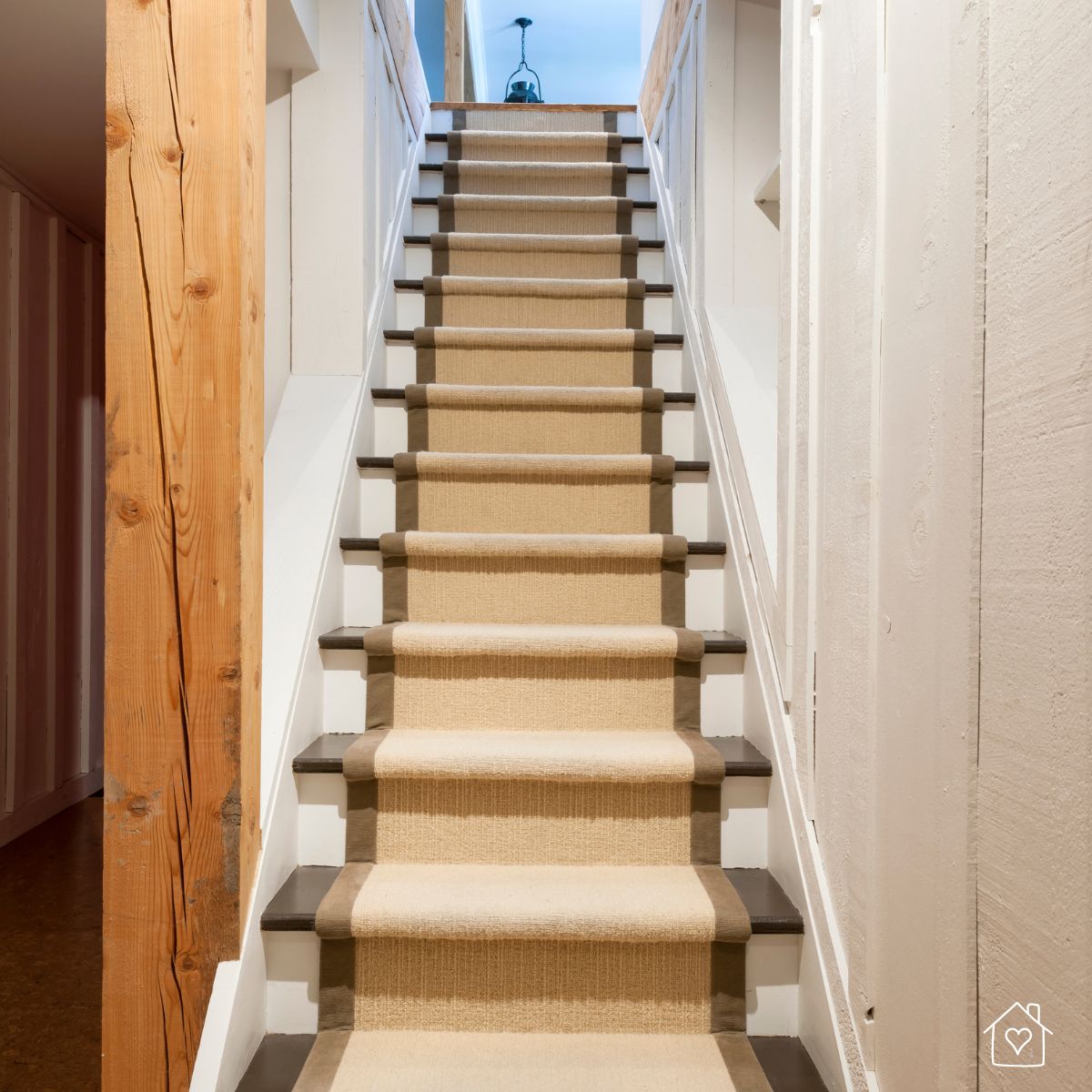 Staircase with a beige runner bordered in brown, installed between white walls and natural wood accents