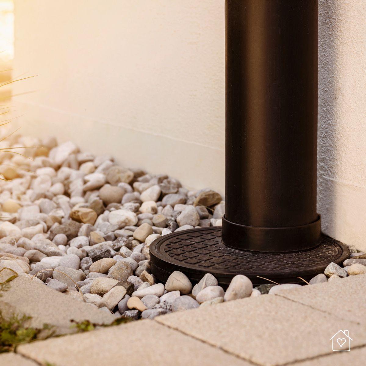Close-up of a downspout emptying directly near the foundation, showing a common issue that can lead to water pooling and structural damage.