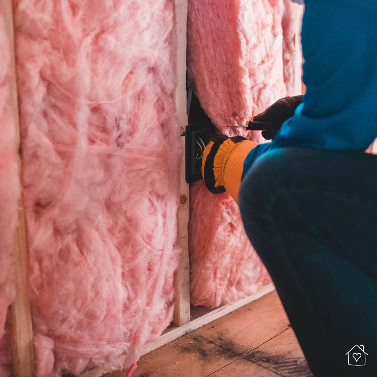 Close-up of a contractor adding pink fiberglass insulation to a basement wall cavity—part of sealing and moisture-proofing against radon and mold