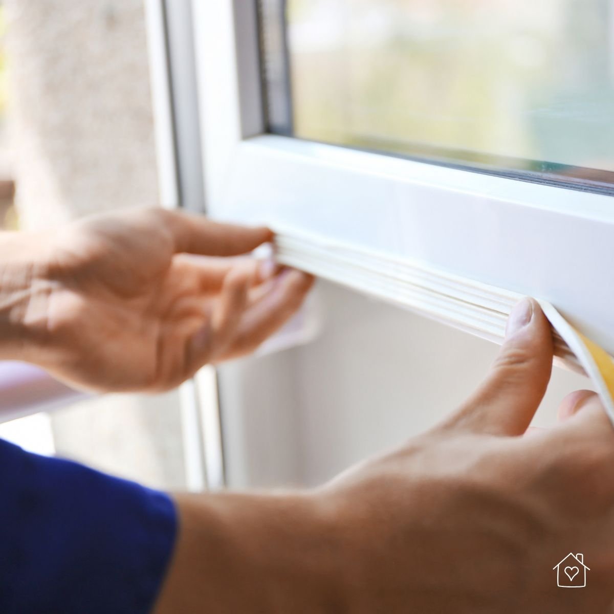 Close-up of hands applying weather sealant to a window frame to prevent drafts and moisture.