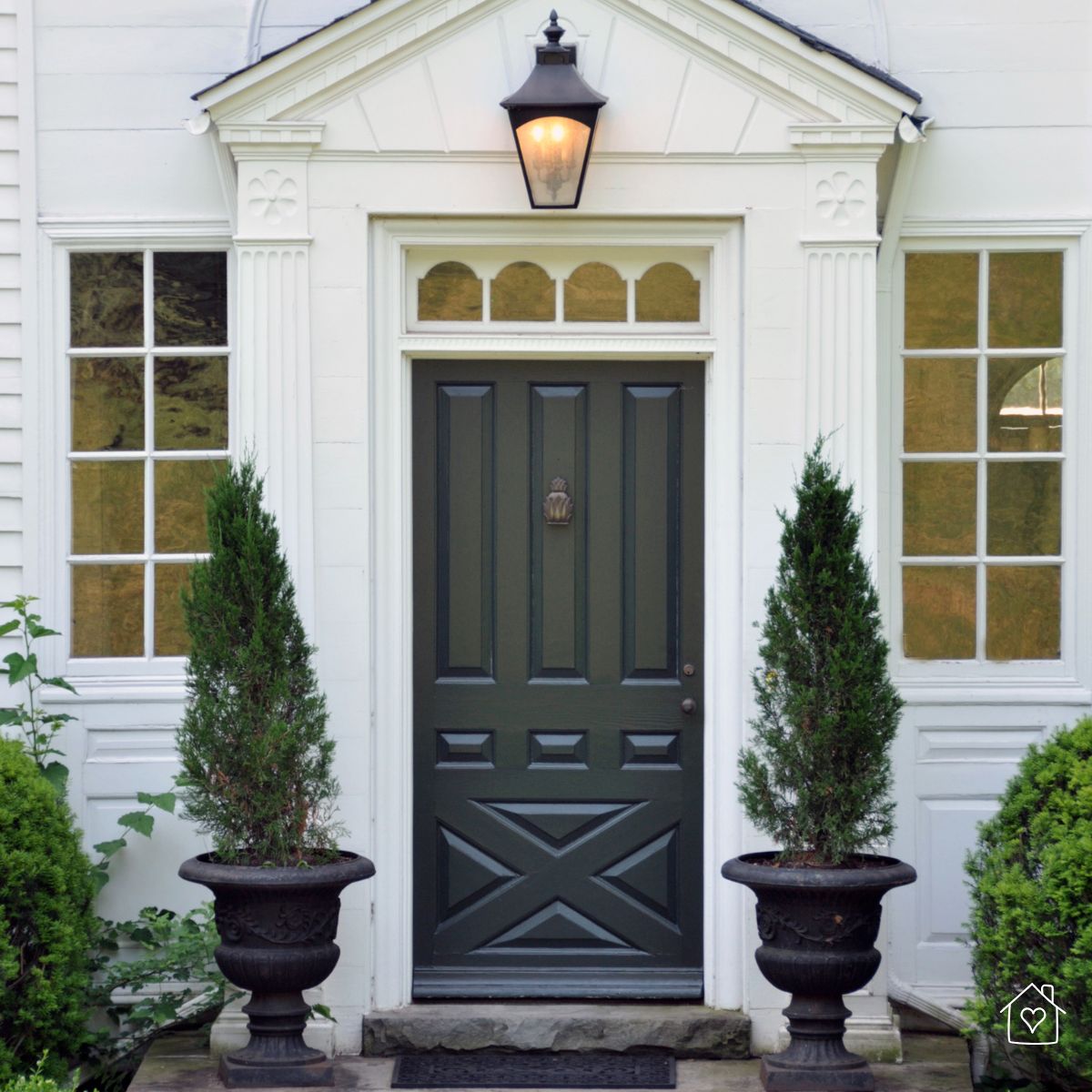 Elegant black front door with ornate molding and tall planters, standing strong against daily weather exposure.