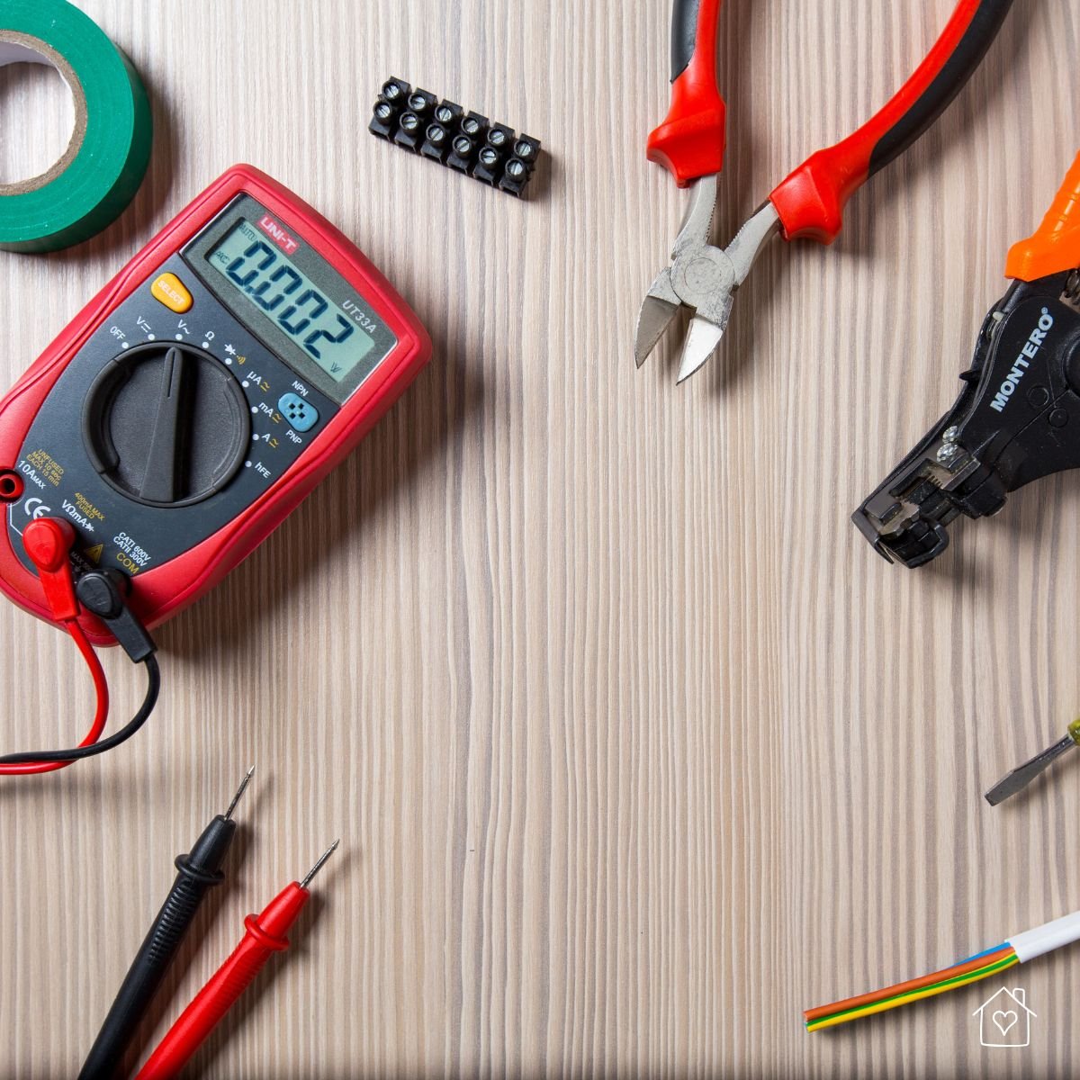 Multimeter, wire cutters, tape, and other electrical tools neatly arranged on a wooden surface, ideal for DIY or professional appliance repair work.