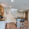Stylish basement with kitchen island, bar stools, and barn door—demonstrating the benefits of a finished and well-insulated basement space