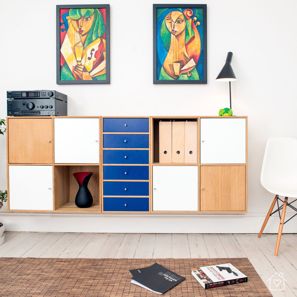 Minimalist home interior display with mid-century modern storage units, colorful abstract wall art, and contemporary lighting.