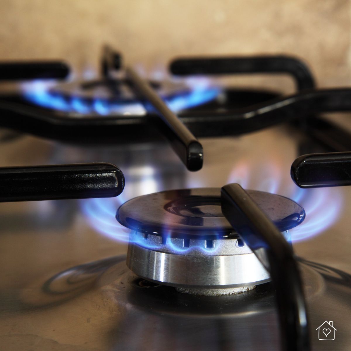 Close-up of a lit gas stove burner with a clean blue flame, showcasing the importance of maintaining well-functioning household parts for energy efficiency.