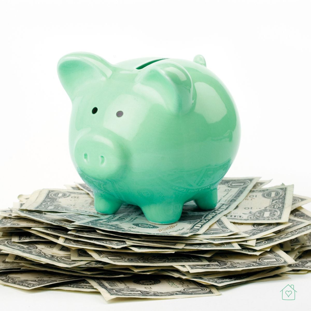 A green piggy bank sitting on a stack of dollar bills representing savings, lower interest rates, and financial planning with personal loans.