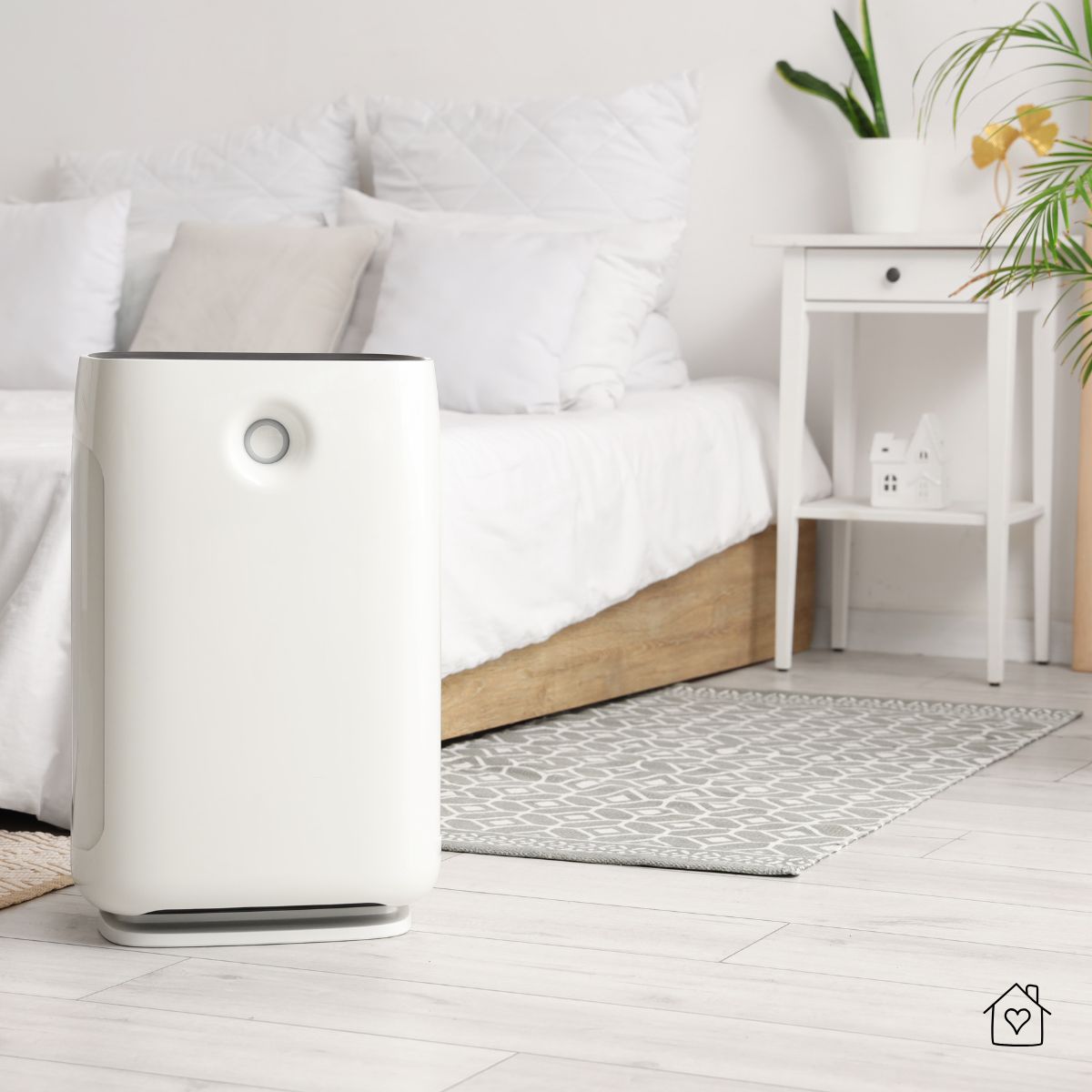 Sleek white air purifier placed beside a bed in a bright bedroom for clean air while sleeping.