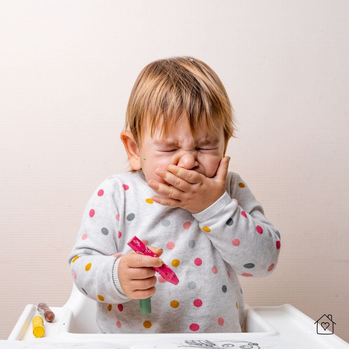 Young child sneezing while holding markers, showing allergy symptoms caused by poor indoor air quality.