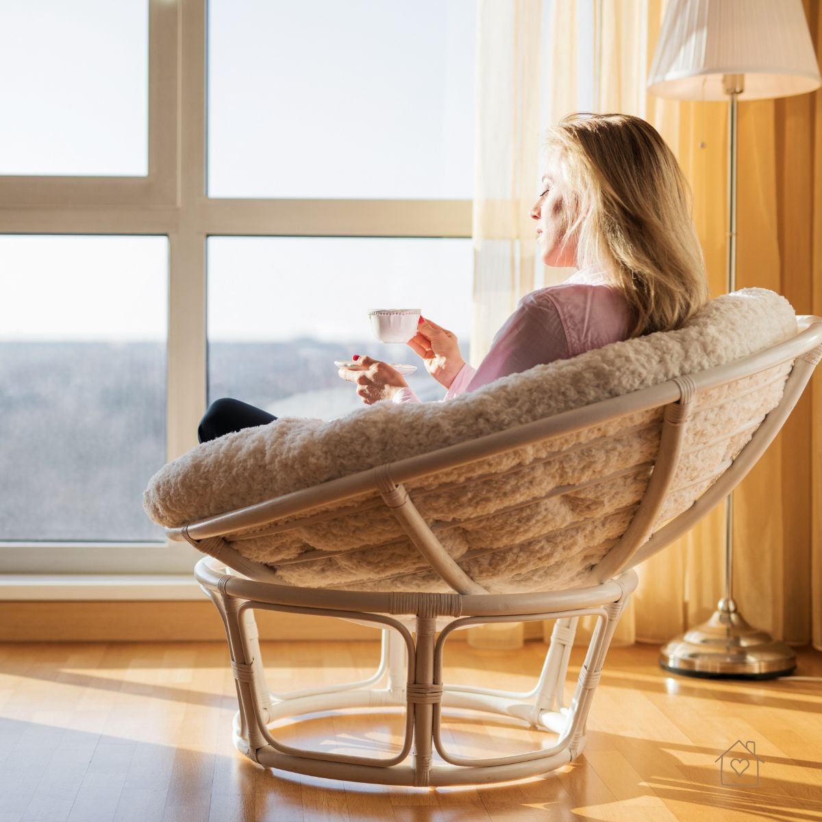 Woman sitting in a cozy chair by a sunny window, sipping coffee and enjoying quiet morning me-time.