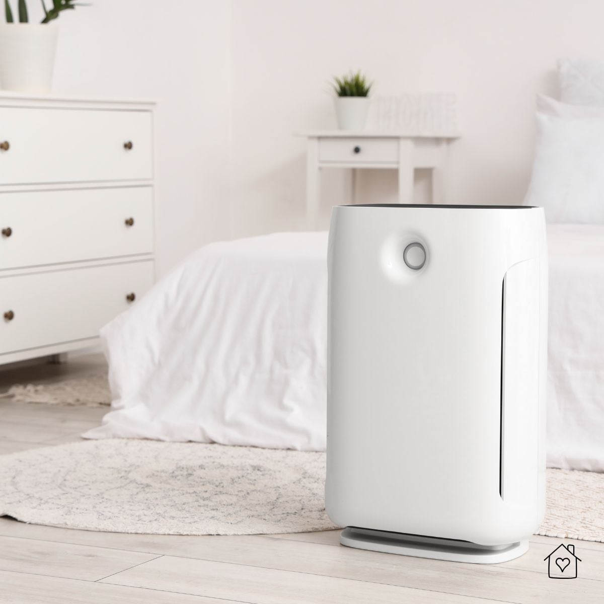 Air purifier placed in a soft, cozy bedroom with white bedding for improved sleep quality.