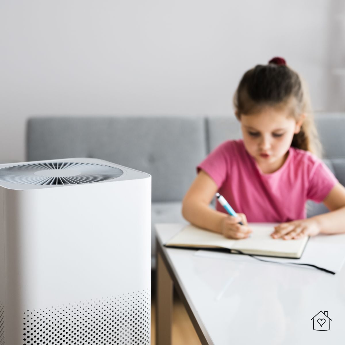 Child studying at a desk with an air purifier nearby, helping reduce allergens and pollutants.