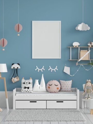 White daybed against a blue wall decorated with hot air balloon and cloud accents, plush pillows, and whimsical wall art.