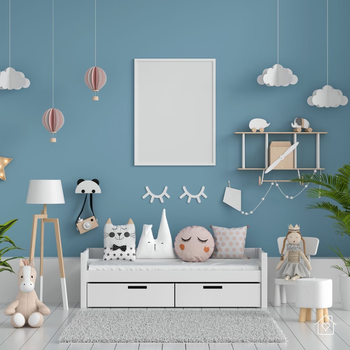 White daybed against a blue wall decorated with hot air balloon and cloud accents, plush pillows, and whimsical wall art.