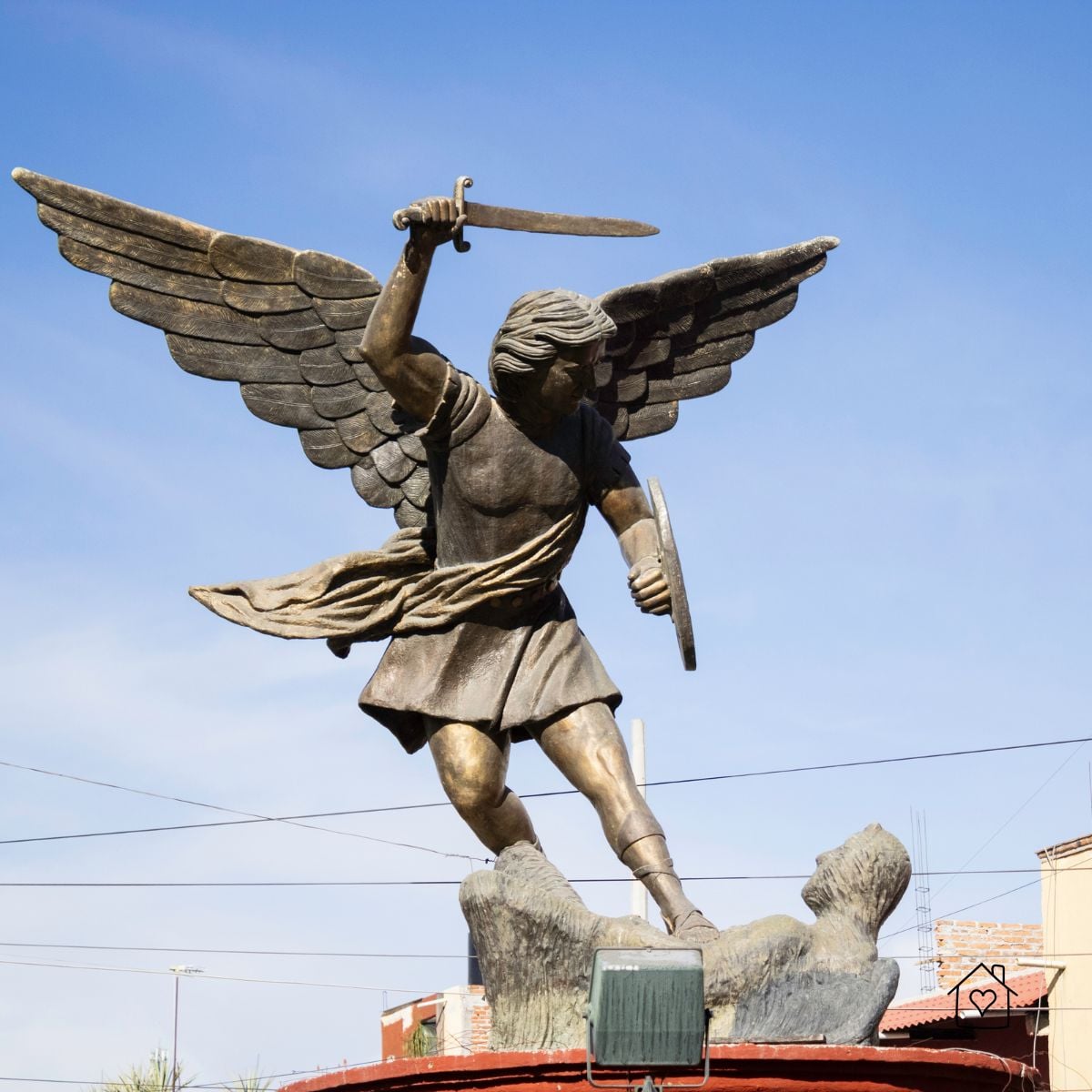 Winged statue of Saint Michael holding a sword and shield against a blue sky in San Miguel de Allende, Mexico.