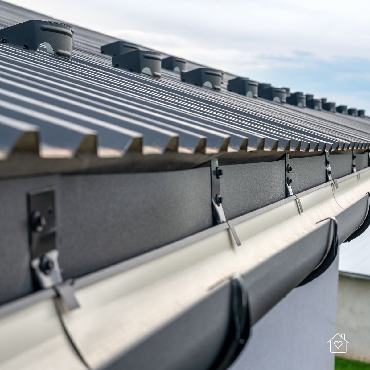 Close-up of standing seam metal roof with secure gutter system and brackets.