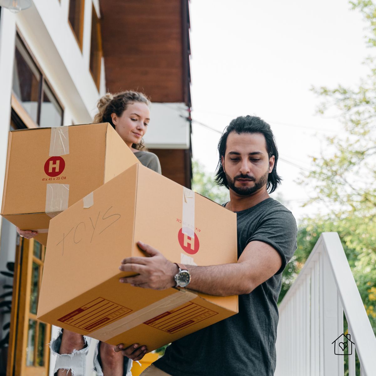 Young couple carrying moving boxes while relocating to a new house in California