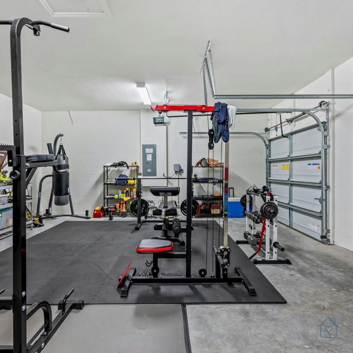 Garage transformed into a home gym with weightlifting equipment, punching bag, and rubber flooring.