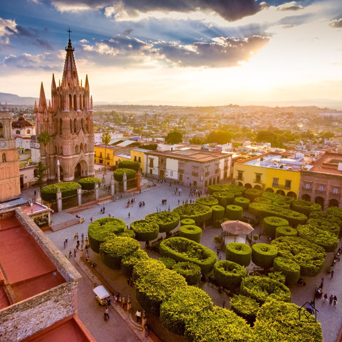 Aerial view of Jardín Allende and the pink spires of La Parroquia de San Miguel Arcángel at sunset in San Miguel de Allende, Mexico.
