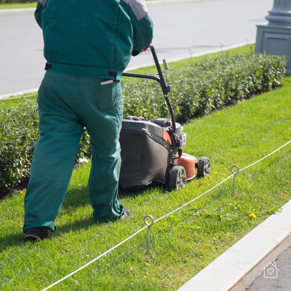 Professional landscaper pushing a mower along a curb and hedge, a scenario where high-lift blades shine for strong suction and tidy bagging.