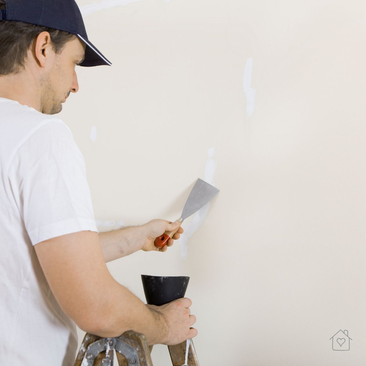 Homeowner filling nail holes with spackling and a putty knife—essential wall prep for a flawless paint job.