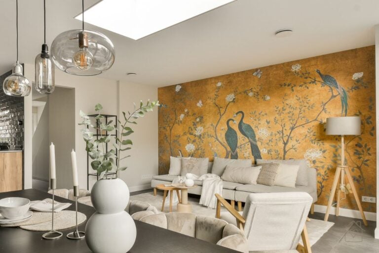 Contemporary living space featuring a gold wall mural with peacocks and floral patterns, paired with minimalist furniture and pendant lighting.