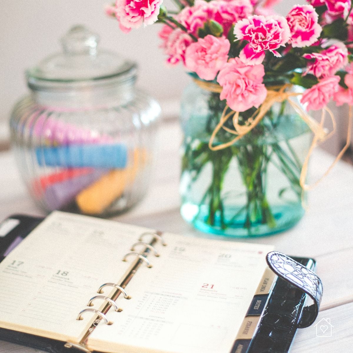 Open daily planner with a vase of pink flowers, symbolizing an organized decluttering schedule.