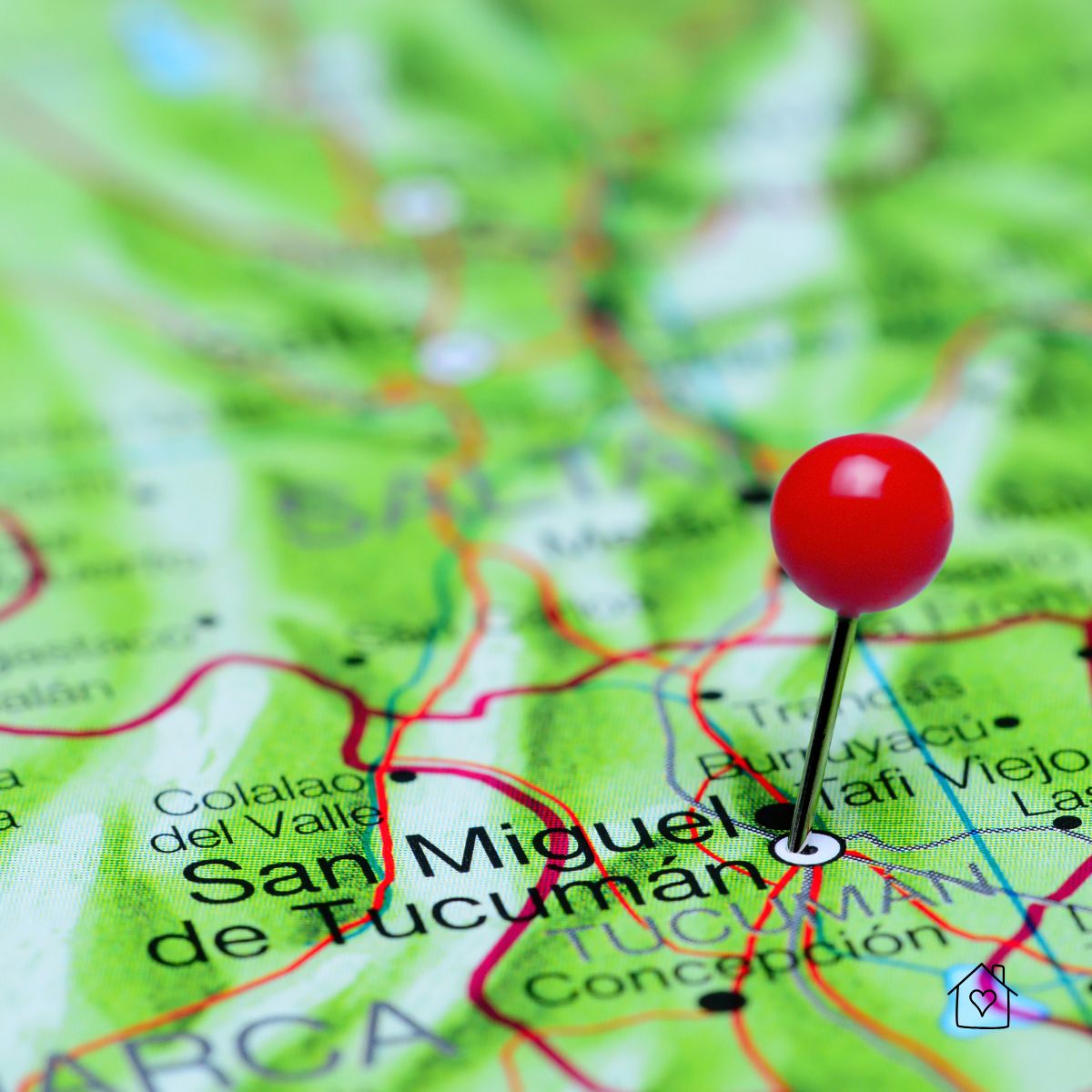 Close-up of a red pushpin marking San Miguel de Tucumán on a green road map of Argentina.